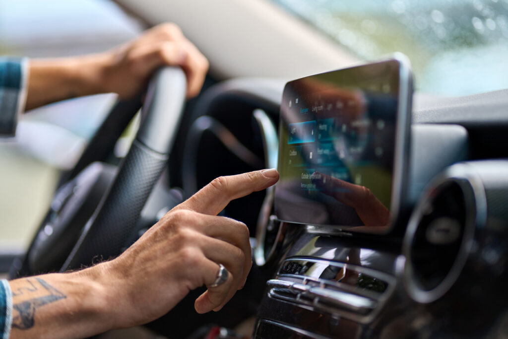 Man traveler sitting in car using gps navigation on monitor while driving.