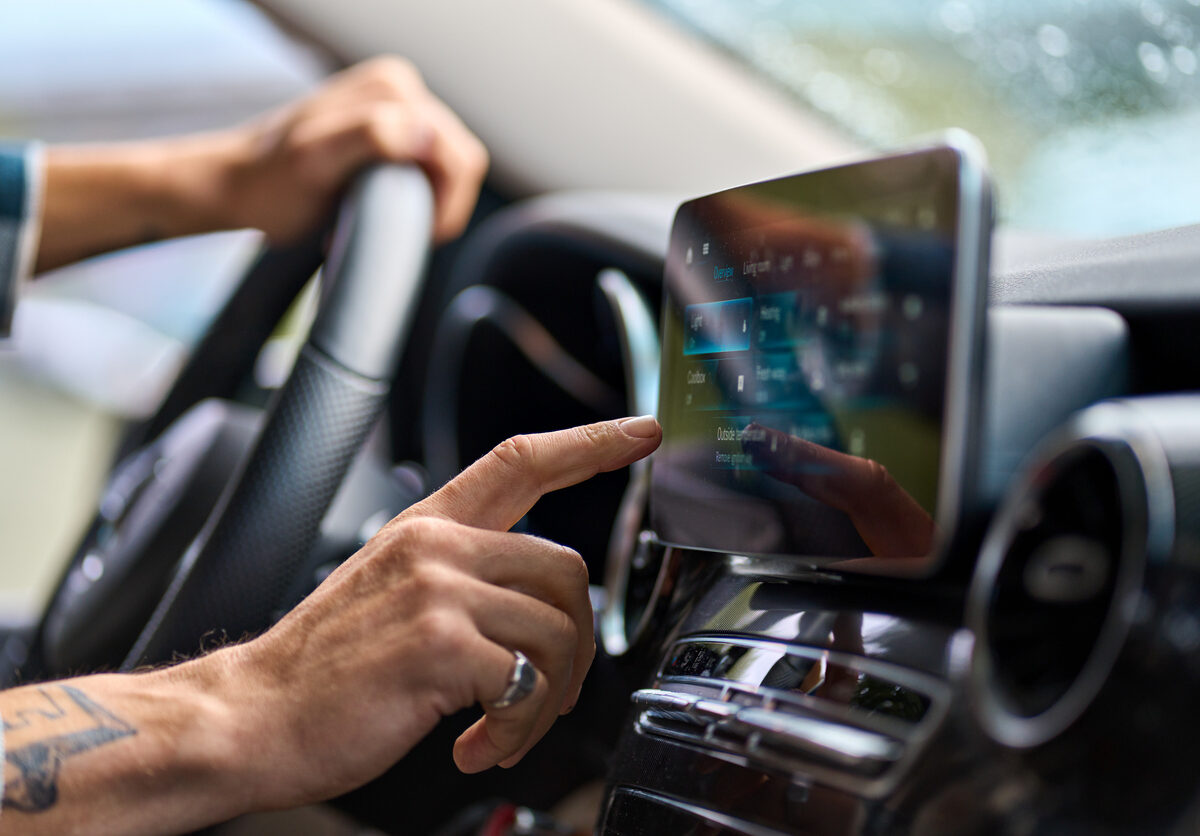 Man traveler sitting in car using gps navigation on monitor while driving.