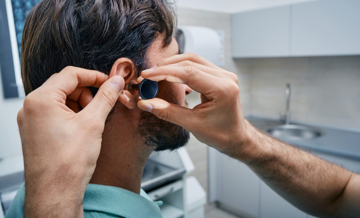ENT doing professional examination of male patient's ear in his office at medical clinic. Ear check-up, close-up