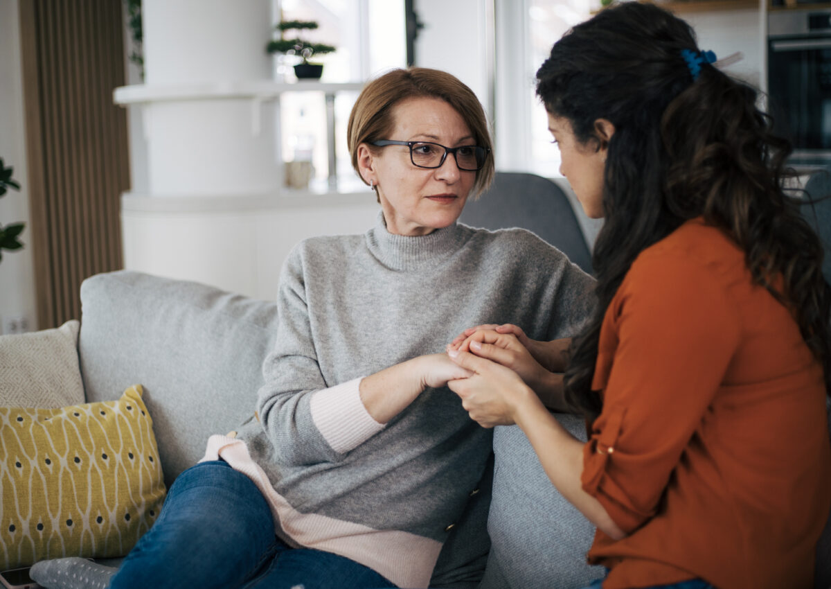 Mother and daughter talking to each other and holding hands