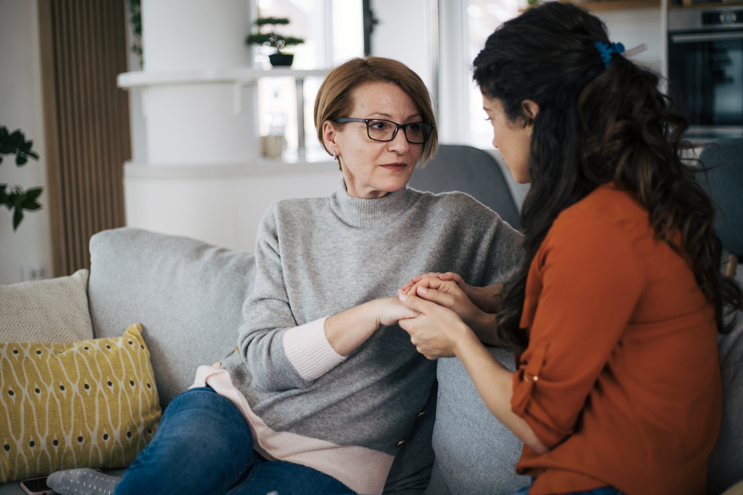 Mother and daughter talking to each other and holding hands