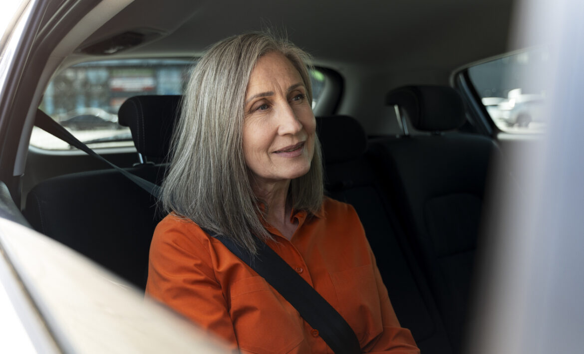 Smiling confident senior with safety belt sitting inside comfortable car. Road trip, transportation concept