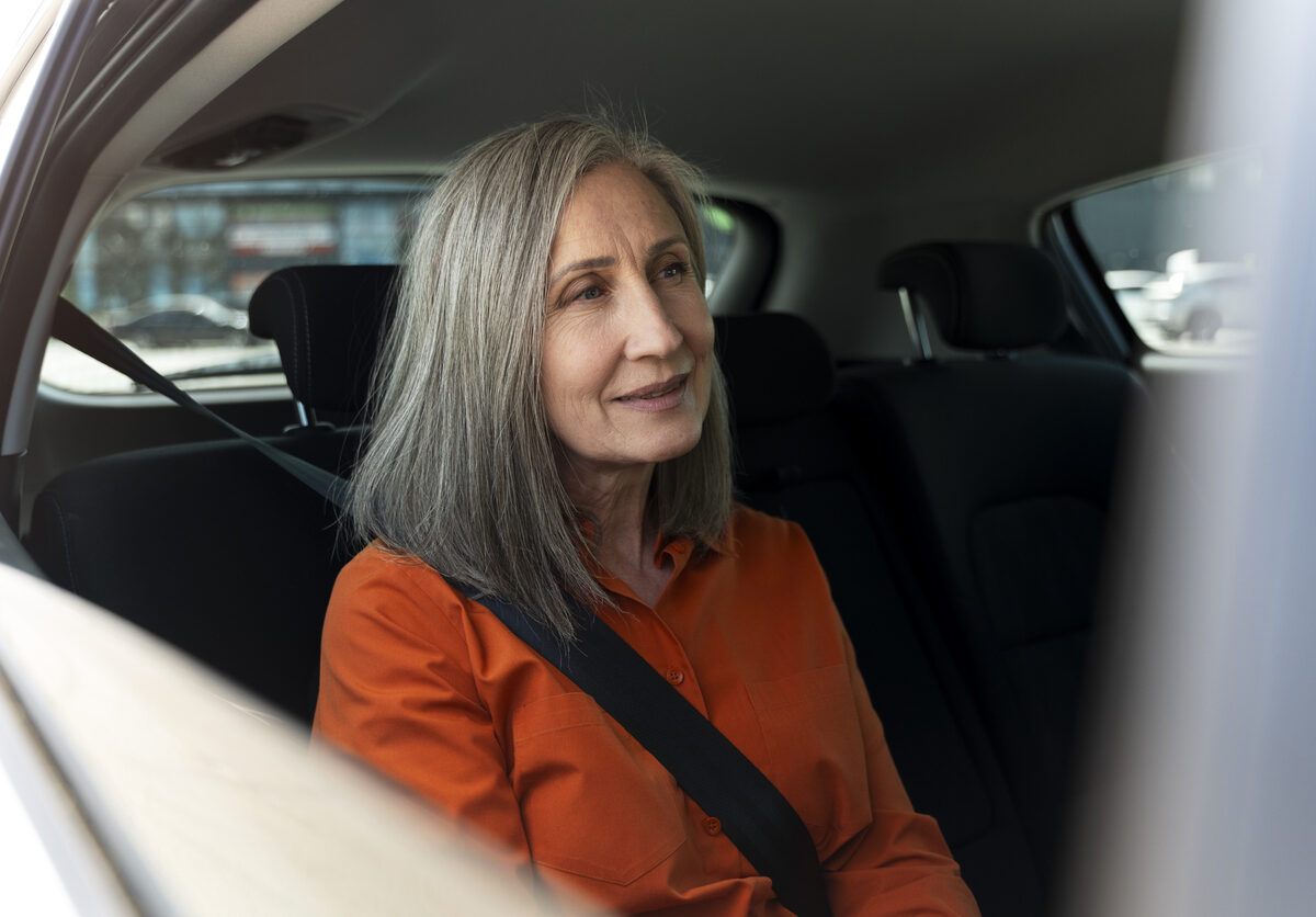 Smiling confident senior with safety belt sitting inside comfortable car. Road trip, transportation concept