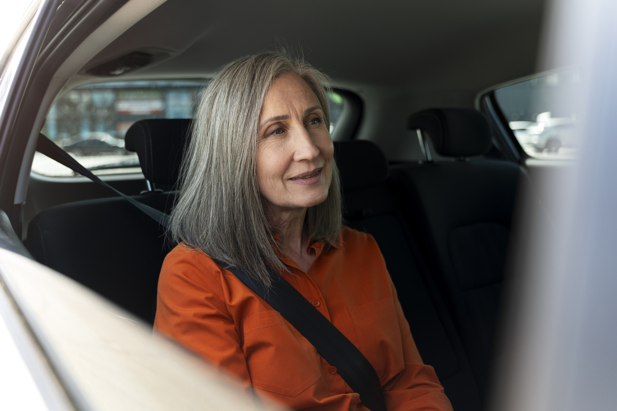 Smiling confident senior with safety belt sitting inside comfortable car. Road trip, transportation concept